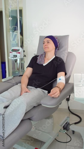 Woman undergoing chemotherapy treatment in oncology center, seated in medical recliner with intravenous infusion, cancer care, recovery and healthcare support