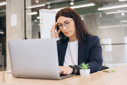 Konstfotografi Stressed businesswoman touching her head, suffering from a headache while workin