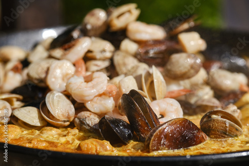 Large seafood paella pan being served outdoors. Hot Spanish Paella. Selective focus.