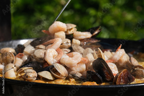 Large seafood paella pan being served outdoors. Selective focus.