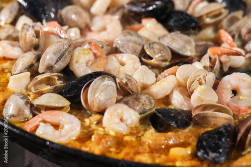 Cooking paella with seafood. Large seafood paella pan. Selective focus.