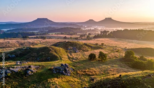 Sunset over historical stone walls and green hillside landscape.
