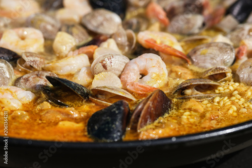 Large seafood paella pan being served outdoors. Hot Paella. Selective focus.