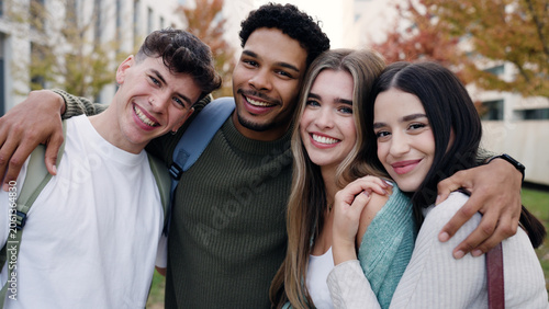 Group of happy young students smiling and embracing on a university campus, celebrating friendship and education outdoors