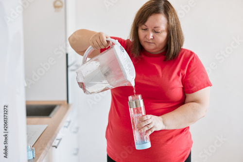 Woman pouring drinking water into reusable bottle