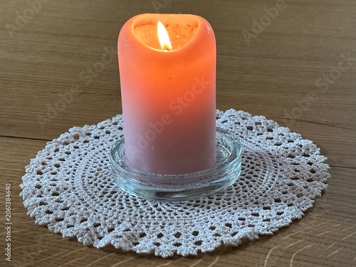 burning candle on a white background standing on a wooden table
