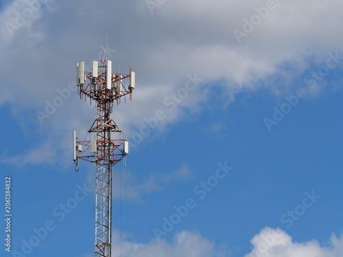 Cell phone tower site or cell base tower or cellular base station with white cloud and blue sky in background