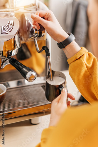 Barista steaming milk in a pitcher with coffee machine