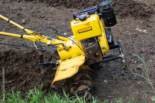 Obraz na płótnie Yellow power tiller working in agricultural field