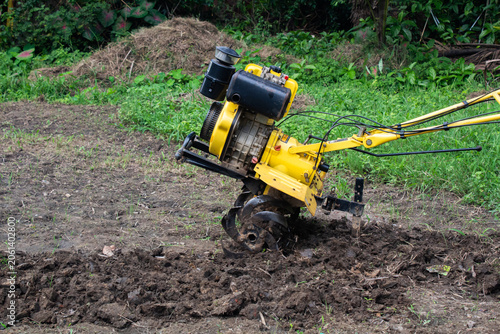 Power tiller plowing wet agricultural soil