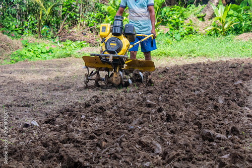 Obraz na płótnie Power tiller operating on freshly cultivated field