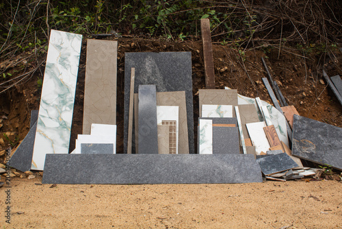 Stack of various leftover construction tiles and granite slabs outdoors