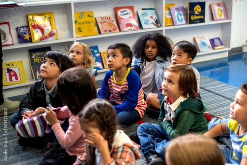 Billede på lærred Diverse group of children sitting on the floor in a library setting