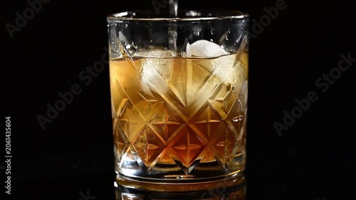 Close-up of metal spoon stirring ice in cocktail glass, mixing drink slowly, ice cubes spinning in liquid, refreshing beverage preparation, professional bartending, alcoholic or non-alcoholic cocktail