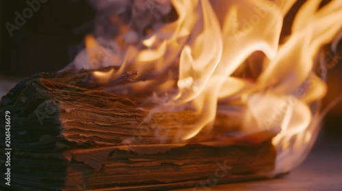 Burning old book at night in a dark room with strong flames and smoke rising up