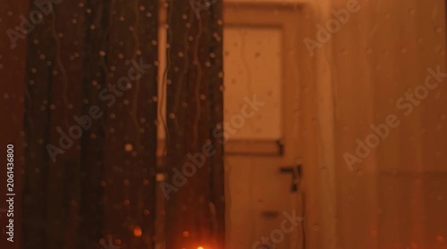 Candles and pumpkins placed by a window during a rainy evening in autumn
