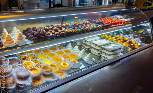 Fotografie A glass display case in a confectionery shop filled with various Brazilian sweets like brigadeiros, quindins, pastel de nata, honey cakes (pão de mel), and assorted chocolates