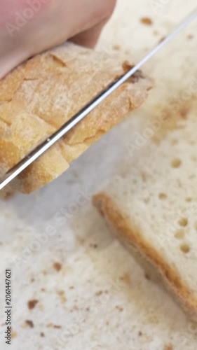 Vertical: A rustic crusty bread loaf is carefully sliced revealing its airy soft interior, the perfect base texture needed for crisp golden bruschetta served at the celebration event.