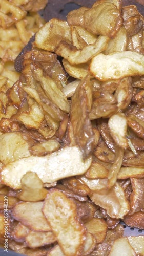Vertical: A large tray filled with golden crispy french fries sits ready to be served, a simple crowd-pleasing side dish prepared for guests at the busy catered restaurant party event.