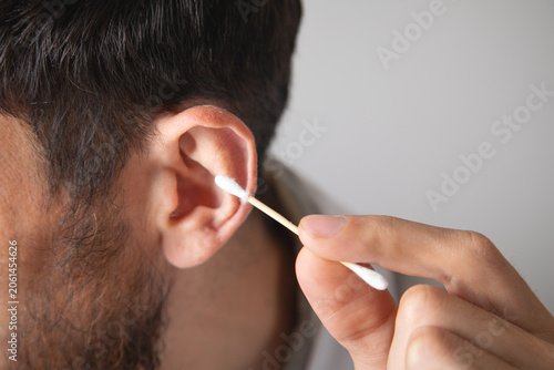 Caucasian man showing cotton bud for ear cleaning.