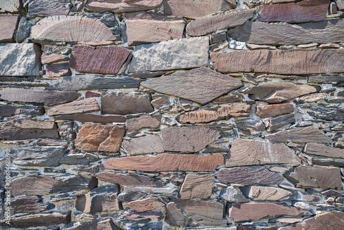 Photograph showcasing rugged limestone and granite wall with moss and shadow play for artistic projects