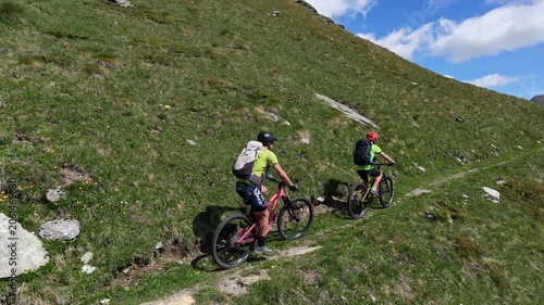 Torgnon, Valle d'Aosta, Italy: Two Mountain Bike Riders Navigating Steep Path Leading to a Beautiful Panorama