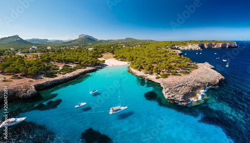 aerial view of scenic mallorca beach and turquoise bay with boats in spain balearic islands rocky coastline landscape in summer mediterranean nature and vacation destination from drone