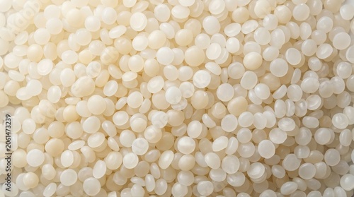 White plastic polymer pellets background texture showing uniform circular resin granules used in industrial manufacturing processes for injection molding production