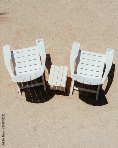 Two White Beach Chairs with Small Table on Sand