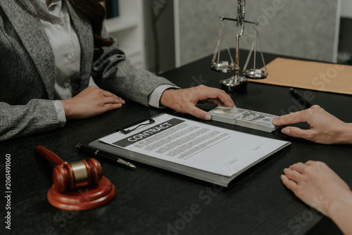 Close-up of person giving bribe money in US dollars to a judge or lawyer at desk.