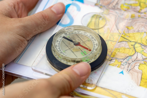 Obraz na plátne Orienteering compass on a topographic map, hands holding navigation equipment, concept of hiking, adventure, travel, and wilderness survival