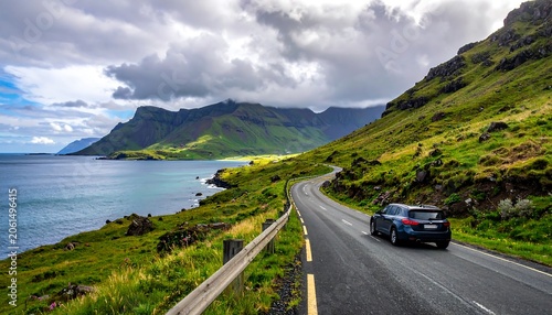 A black car drives on a winding road along a rugged coastline with green hills and mountains