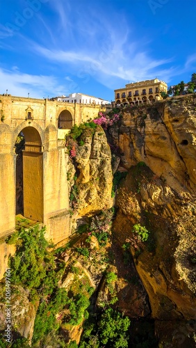A blurry image of an ancient, yellowish stone bridge with arches on a cliffside