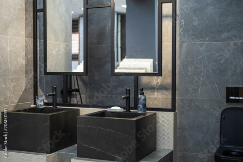 Contemporary bathroom interior featuring a black toilet, stone vessel sink and dark marble-effect wall tiles. Modern residential design, elegant fixtures, minimalist style, premium finishing materials