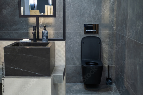 Canvastavla Contemporary bathroom interior featuring a black toilet, stone vessel sink and dark marble-effect wall tiles