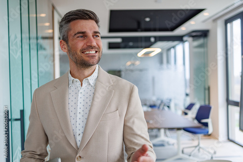 Fotografie Happy professional businessman standing in a boardroom, expressing optimism, vis