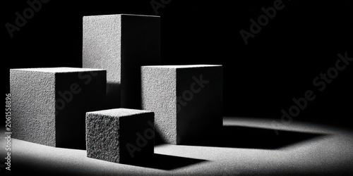 Geometric Abstraction: Four abstract cubic forms are arranged in a composition of light and shadow, highlighting their texture and form against a stark, dark background.