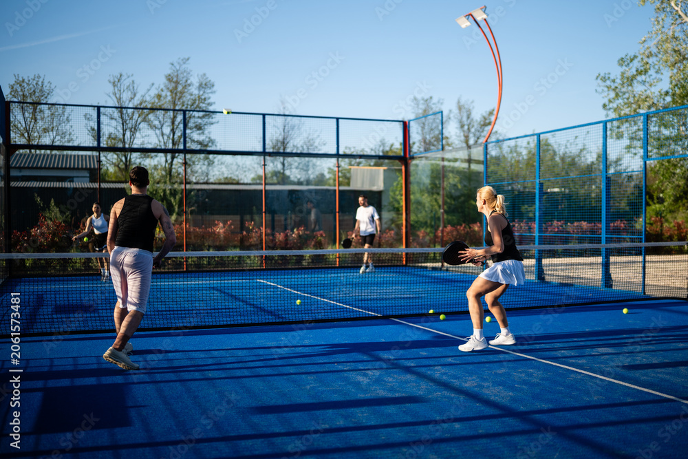 Naklejka premium Four friends playing padel tennis match outdoors