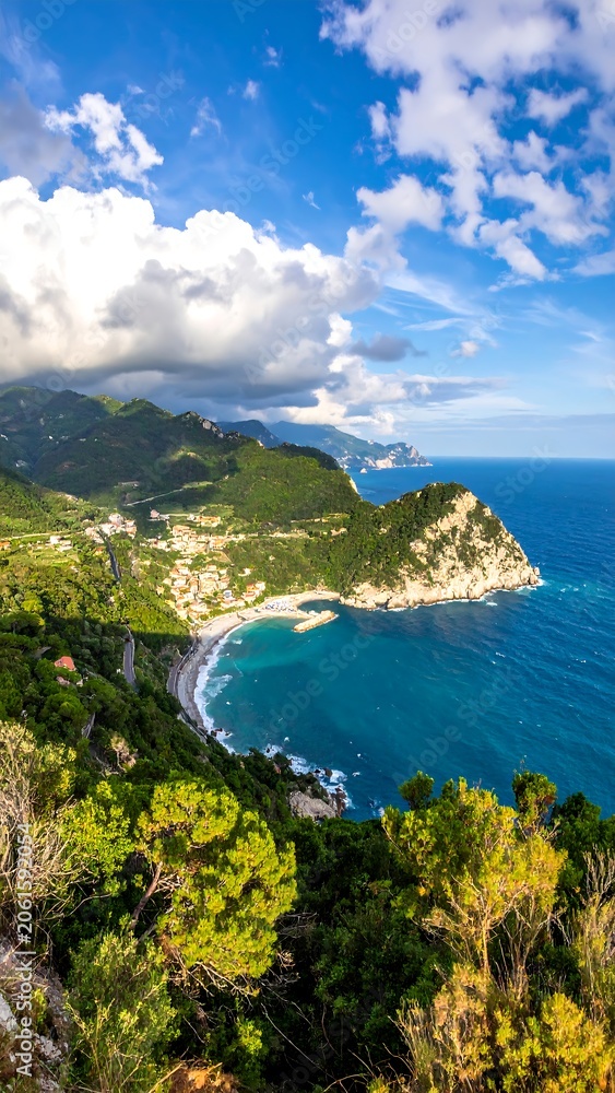 Fototapeta premium Aerial view of a serene coastline with lush greenery and a vibrant blue sea under a partly cloudy sky