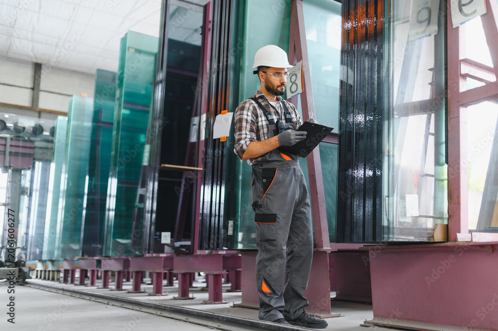 Fototapeta premium Factory worker inspecting glass panels in manufacturing plant