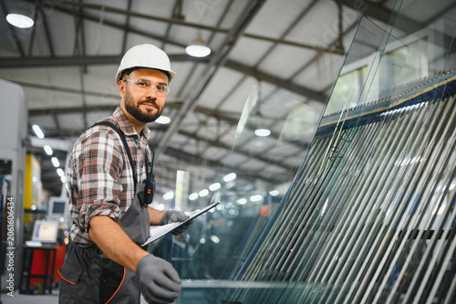 фотографія Worker checking glass panels in window factory