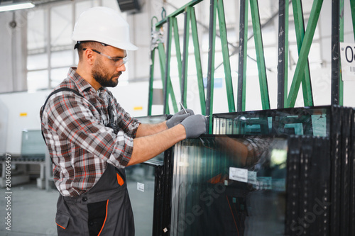 Принти на полотні Worker inspecting glass panels in factory production