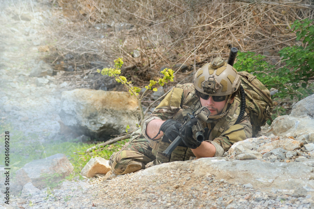 Fototapeta premium The sacrificing soldiers lie prostrate on the ground camouflaged behind rocks preparing fire upon the enemy on the ground in a ready to attack stance.