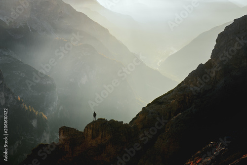 Quadro em tela A lone hiker stands on a rocky ridge above Cortina d'Ampezzo at sunrise in the Dolomites