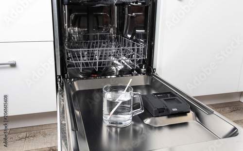 Water hardness measurement using test strip on open dishwasher door against background of kitchen appliance