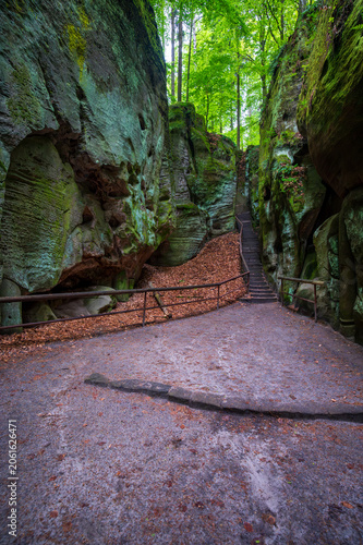 Massive sandstone rock formations along a forest trail in Bohemian Paradise (Cesky raj), Hruba Skala area (Hruboskalsko), Czech Republic, with giant stones rising above woodland path