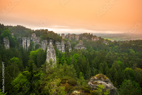 Rock city formations in Hruba Skala, Bohemian Paradise (Cesky raj), rising from forest seen from above. Orange sunrise sky lights sandstone towers and valleys panoramic view sky .
