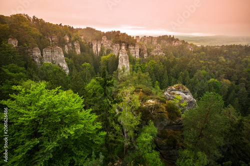 Rock city formations in Hruba Skala, Bohemian Paradise (Cesky raj), rising from forest seen from above. Orange sunrise sky lights sandstone towers and valleys panoramic view sky .
