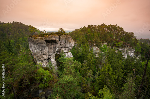 Rock city formations in Hruba Skala, Bohemian Paradise (Cesky raj), rising from forest seen from above. Orange sunrise sky lights sandstone towers and valleys panoramic view sky .