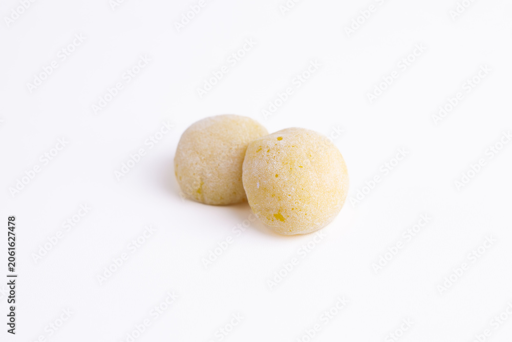 Fototapeta premium Two yellow mochi covered in powder on a white background. Traditional japanese sweet dessert ready for advertising layout. 